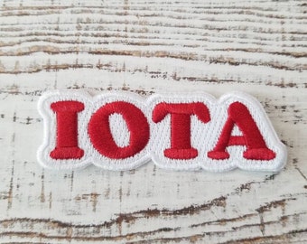 May include: White embroidered patch with the word "IOTA" in red lettering.