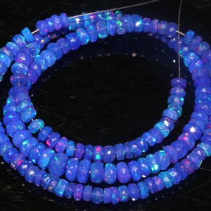 May include: A strand of blue opal beads with iridescent shimmer. The beads are faceted and have a slightly irregular shape. The strand is strung on a clear thread and is ready to be used for jewelry making.