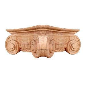 Może przedstawiać: Rzeźbiony drewniany element architektoniczny, prawdopodobnie kapitel, z misterne wzory zwojów i wolut. Widoczne jest naturalne usłojenie drewna, a element ma jasnobrązowy kolor. Tekst "perfectcarvings" jest widoczny na dole.