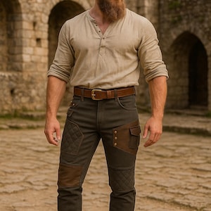 Puede incluir: Una persona con una camisa henley color beige, cinturón marrón y pantalones verde oliva con detalles de cuero marrón. Los pantalones tienen rodilleras acolchadas y bolsillos. Botas de cuero marrón completan el conjunto.