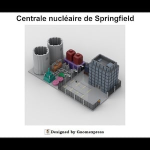 May include: A miniature model of the Springfield Nuclear Power Plant, featuring two large cooling towers, a multi-story building, and various other structures. The model is set on a rectangular base with the text "Centrale nucléaire de Springfield" and "Designed by Gnomexpress".