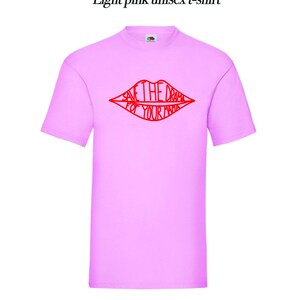 May include: Light pink unisex t-shirt with a red graphic of a pair of lips with the text "Save the drama for your mama" inside.