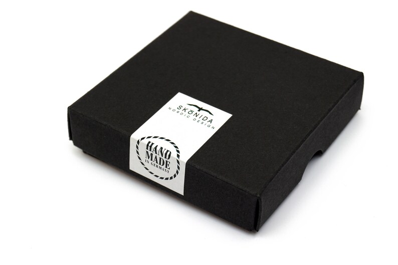 Op de afbeelding: Een zwarte doos met een wit label waarop "Sk&ouml;nida Nordic Design" en "Hand Made in Germany" staat.