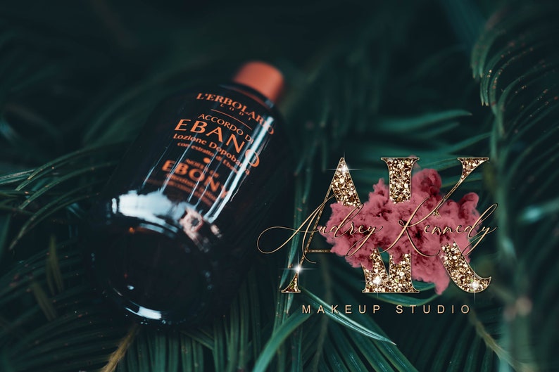 May include: A dark brown glass bottle with a gold label that reads "L'Erbolario Accordo di Ebano Lozione Dopobarba" and "Ebano" in a gold font. The bottle is sitting on a bed of green leaves.