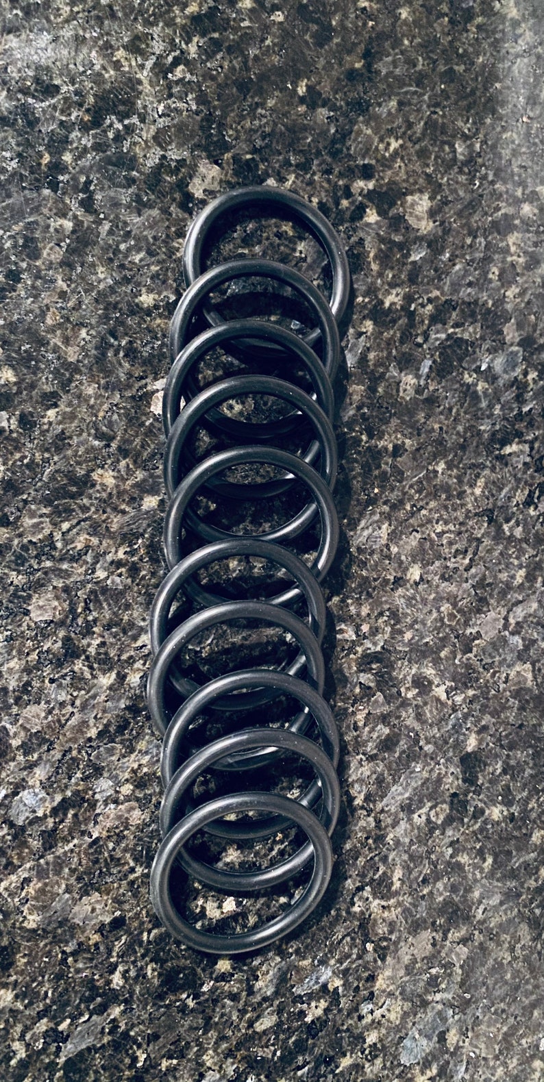 May include: A stack of ten black rubber O-rings.