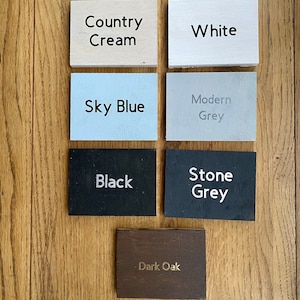 May include: Six wooden samples of different colors and finishes. The colors are Country Cream, White, Sky Blue, Modern Grey, Black, and Stone Grey. The last sample is Dark Oak.