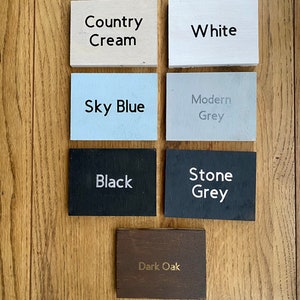 May include: Six wooden samples of different colors and finishes. The colors are Country Cream, White, Sky Blue, Modern Grey, Black, and Stone Grey. The last sample is Dark Oak.