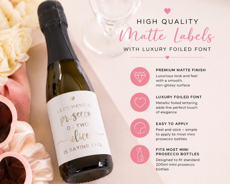 May include: A mini prosecco bottle with a white matte label featuring gold foil text that reads Let's have a prosecco or two Alice is saying I do. The label includes a small heart icon and is designed for 200ml mini prosecco bottles.