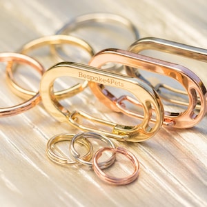 Könnte beinhalten: Ein Satz Schlüsselanhänger in Gold, Roségold und Silber mit einem großen ovalen Schlüsselanhänger, der mit dem Text "Bespoke4Pets" graviert ist.