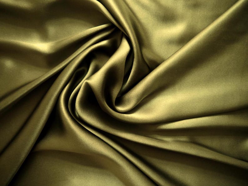May include: Close-up of olive green satin fabric with soft folds and highlights. The fabric has a smooth, luxurious texture and a subtle sheen. The folds create shadows and depth, enhancing the fabric's visual appeal. Ideal for apparel, home decor, and craft projects.