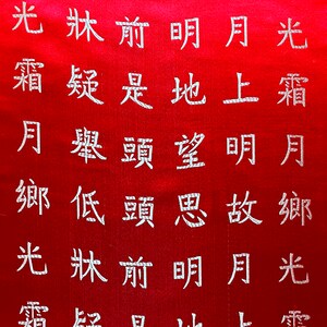K&ouml;nnte beinhalten: Roter Stoff mit wei&szlig;en chinesischen Schriftzeichen, die auf der Oberfl&auml;che gestickt sind. Der Text ist in vertikalen Spalten angeordnet und wird von oben nach unten, von rechts nach links gelesen. Der Stoff hat einen leichten Glanz.