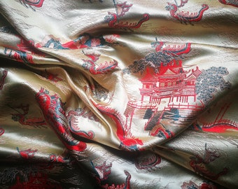 May include: Gold-colored fabric with a detailed pattern featuring red dragons and pagodas. The fabric has a satin sheen and is draped, showing the intricate design and texture. The overall theme is Asian-inspired.