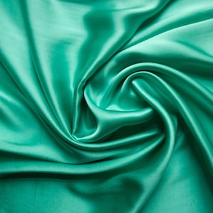 May include: Close-up of a vibrant, flowing fabric in a teal green hue. The material is smooth and lustrous, with soft folds and a swirling pattern. The fabric's sheen suggests a satin or silk texture, ideal for apparel or home decor.