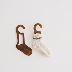 May include: Two wooden sock hangers, one with a white sock with a black stripe hanging on it.