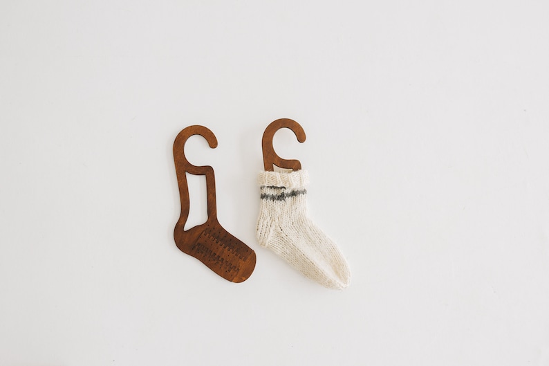 May include: Two wooden sock hangers, one with a white sock with a black stripe hanging on it.
