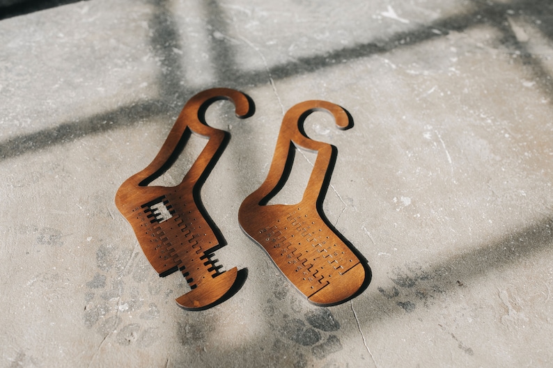 May include: Two wooden sock drying forms with holes for ventilation. The forms are shaped like socks with a hook at the top.