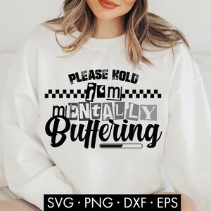 Puede incluir: Sudadera blanca con la frase "PLEASE HOLD I'M MENTALLY BUFFERING" en negro y gris. El diseño incluye una barra de carga. También se muestra el texto "SVG • PNG • DXF • EPS".