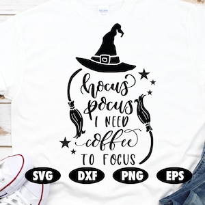 May include: A white t-shirt with a black graphic design that says "Hocus Pocus I Need Coffee To Focus". The graphic includes a witch's hat, stars, and broomsticks.