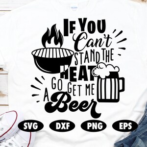 May include: A white t-shirt with a black graphic that says "If you can't stand the heat go get me a beer". The graphic includes a grill with flames and a beer mug.