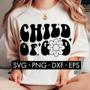 May include: A white t-shirt with a black graphic that says "CHILD OF GOD" in a retro font. The graphic also includes a stylized flower with a yellow center.