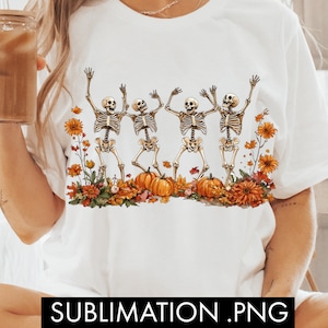 May include: White t-shirt with a graphic of four skeletons dancing with pumpkins and fall foliage. The text "SUBLIMATION.PNG" is at the bottom of the shirt.