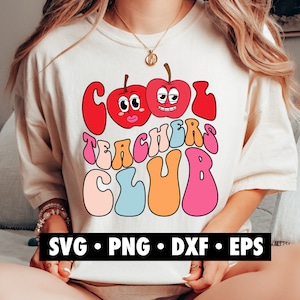 K&ouml;nnte beinhalten: Ein wei&szlig;es T-Shirt mit einem bunten Grafikdesign, auf dem "Cool Teachers Club" steht. Die Grafik zeigt zwei Comic-&Auml;pfel mit Gesichtern und einer Retro-Schriftart.