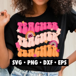 K&ouml;nnte beinhalten: Ein schwarzes T-Shirt mit dem Wort "Teacher" dreimal in einer Retro-Schrift mit rosa, pfirsichfarbenen und orangenen Farben geschrieben. Der Text ist mit Sternen und Regenbogen-Akzenten &uuml;berlagert. Der Text "SVG, PNG, DXF, EPS" ist in Wei&szlig; am unteren Rand des Shirts geschrieben.