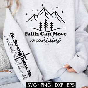May include: A light gray sweatshirt with black text and graphics. The front features a mountain and tree design with the words "Faith Can Move Mountains." The left sleeve has the text "He Strengthens Me, I will not be shaken."