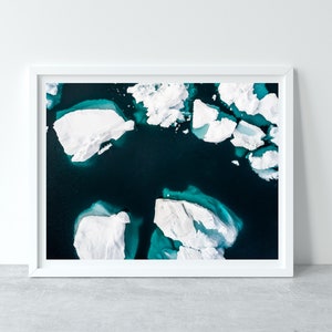 May include: An aerial view of a turquoise blue body of water with white icebergs floating on the surface.