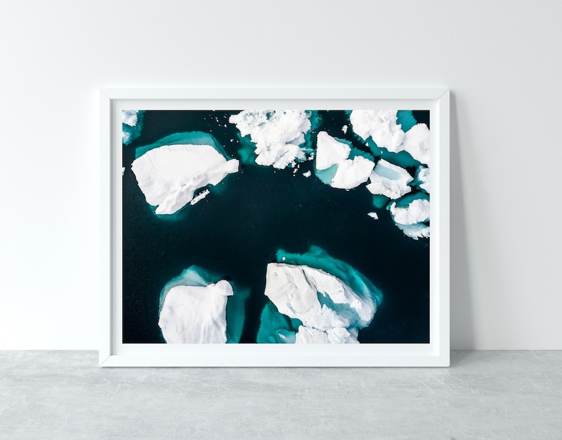 May include: An aerial view of a turquoise blue body of water with white icebergs floating on the surface.