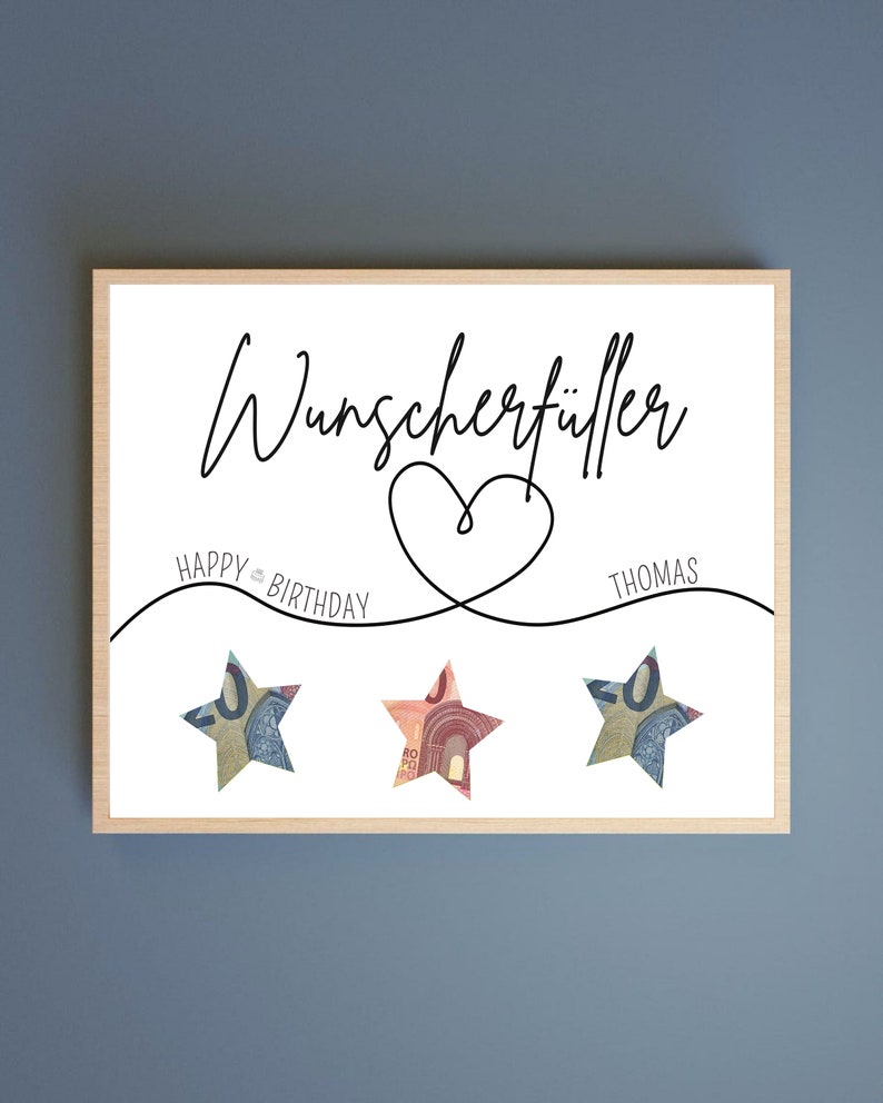 May include: A white card with black text that reads "Wunschersch&ouml;pfer" with a heart drawn around the text. The text "HAPPY BIRTHDAY" is written on the left side of the heart and "THOMAS" is written on the right side of the heart. Three stars are placed below the heart, each made of a 50 Euro bill.