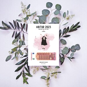 May include: A pink and white card with the text "Abitur 2023" and "Wir sind stolz auf dich Larissa". A cartoon illustration of a person wearing a graduation cap and gown is on the card. A 10 Euro bill with the text "Deine erste Million" is at the bottom of the card.