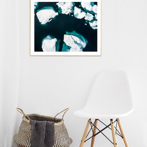 May include: An aerial photograph of a turquoise blue body of water with white icebergs floating on the surface.