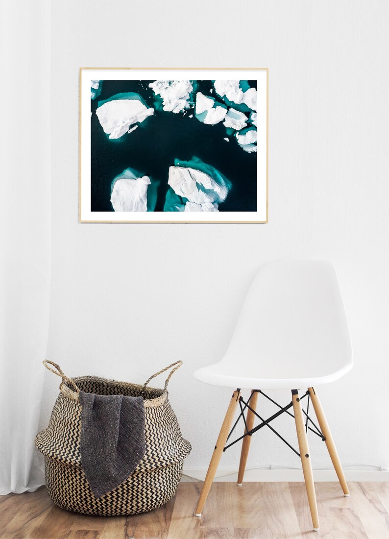 May include: An aerial photograph of a turquoise blue body of water with white icebergs floating on the surface.