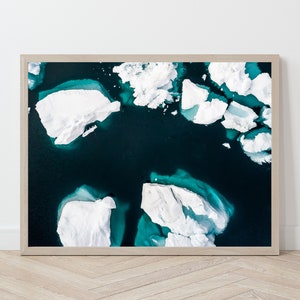 May include: An aerial photograph of a turquoise blue body of water with white icebergs floating on the surface.