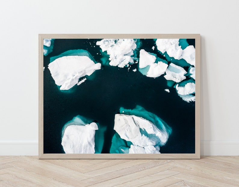 May include: An aerial photograph of a turquoise blue body of water with white icebergs floating on the surface.