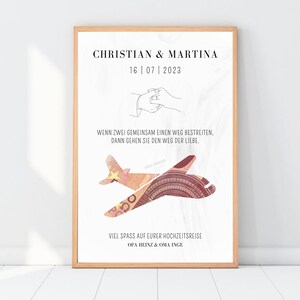K&ouml;nnte beinhalten: Ein gerahmter Druck mit wei&szlig;em Hintergrund und schwarzem Text. Der Text lautet "Christian & Martina 16 | 07 | 2023" und "Wenn zwei Menschen einen Weg gemeinsam gehen, gehen sie den Weg der Liebe." Der Druck zeigt auch ein stilisiertes Bild eines Flugzeugs aus einem 500-Euro-Schein. Der Text unten lautet "Viel Spa&szlig; auf eurer Hochzeitsreise! Opa Heinz & Oma Inge."