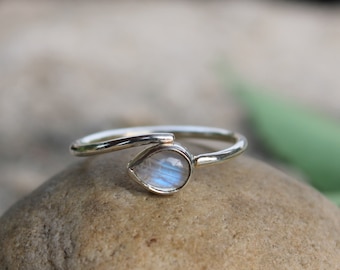 May include: A silver ring with a teardrop-shaped moonstone.