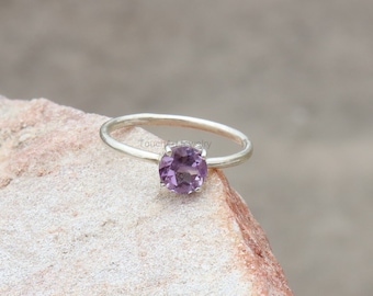 May include: A silver ring with a round, purple amethyst gemstone.
