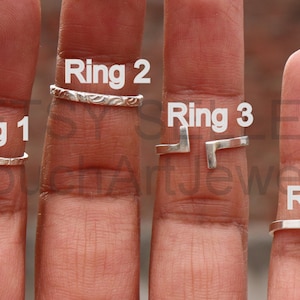 Könnte beinhalten: Vier Silberringe an Fingern, beschriftet Ring 1, Ring 2, Ring 3 und Ring 4.