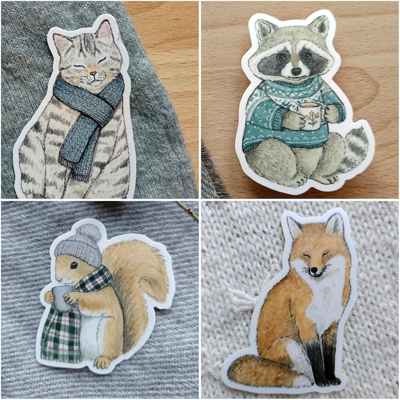 Op de afbeelding: Vier grillige stickers met bosdieren. Een kat met een sjaal, een wasbeer in een trui met een mok, een eekhoorn met een hoed en sjaal, en een vos met gesloten ogen. Elke sticker heeft een witte rand.
