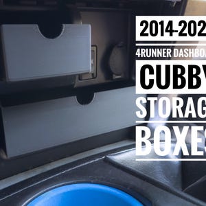 Può includere: Primo piano del cruscotto di un Toyota 4Runner 2014-2024, che mostra due vani portaoggetti etichettati "Cubby Storage Boxes".