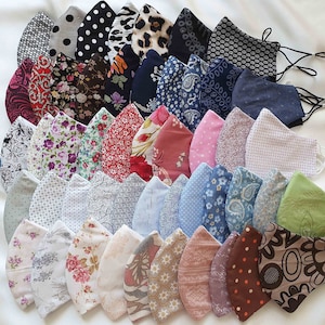 Może przedstawiać: Kolekcja 25 kolorowych masek z tkaniny z różnymi wzorami, w tym kwiatowymi, geometrycznymi i w kropki.