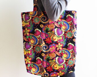 May include: A large black tote bag with a colorful paisley pattern featuring swirls, flowers, and hearts. The bag has long straps and is made of a durable fabric.