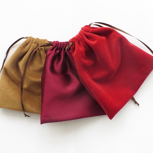 May include: Three velvet drawstring bags in different colours: brown, burgundy and red.