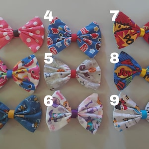 May include: Nine different fabric hair bows with various colorful patterns. The bows are numbered 1 through 9. The patterns include polka dots, sharks, bees, Paw Patrol, basketballs, and superheroes.