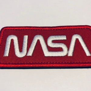 May include: A red embroidered patch with white stitching that reads "NASA".
