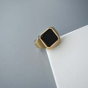 Herren-Siegelring aus Sterlingsilber mit eckigem Onyx und goldener Oberfläche. Das Design ist modern, stark und zeitlos zugleich.