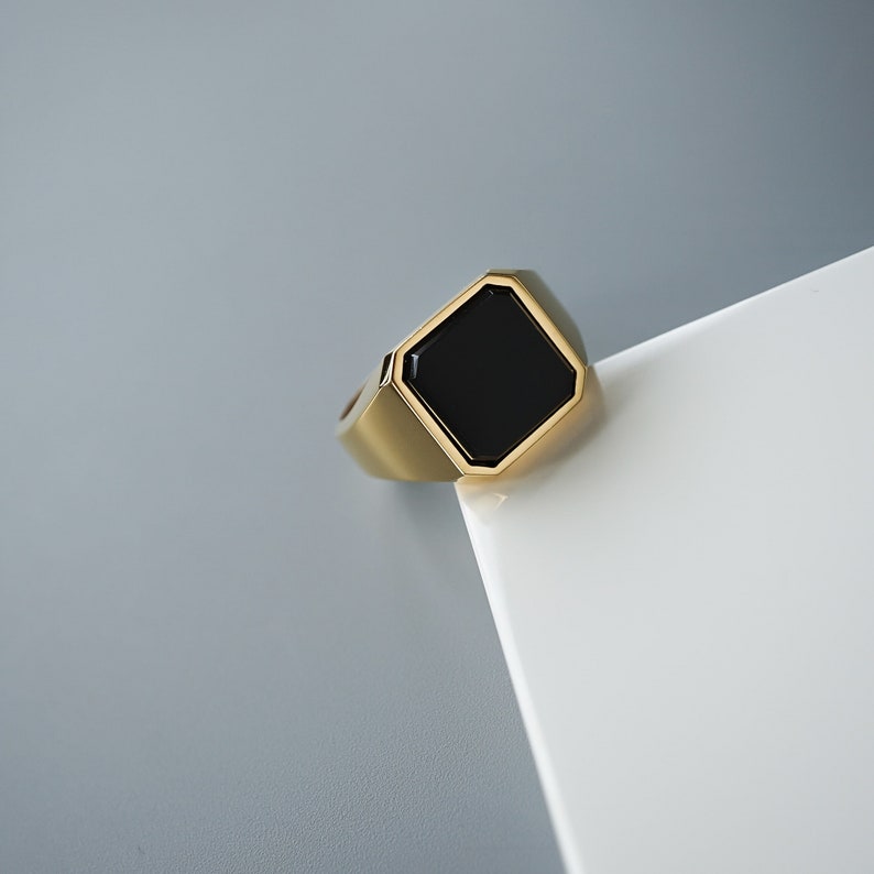 Herren-Siegelring aus Sterlingsilber mit eckigem Onyx und goldener Oberfläche. Das Design ist modern, stark und zeitlos zugleich.