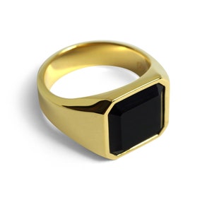 Seitliche Ansicht eines goldenen Herrenrings mit quadratischer Form. Der Kontrast zwischen Onyx und Gold betont die klare Linienführung.